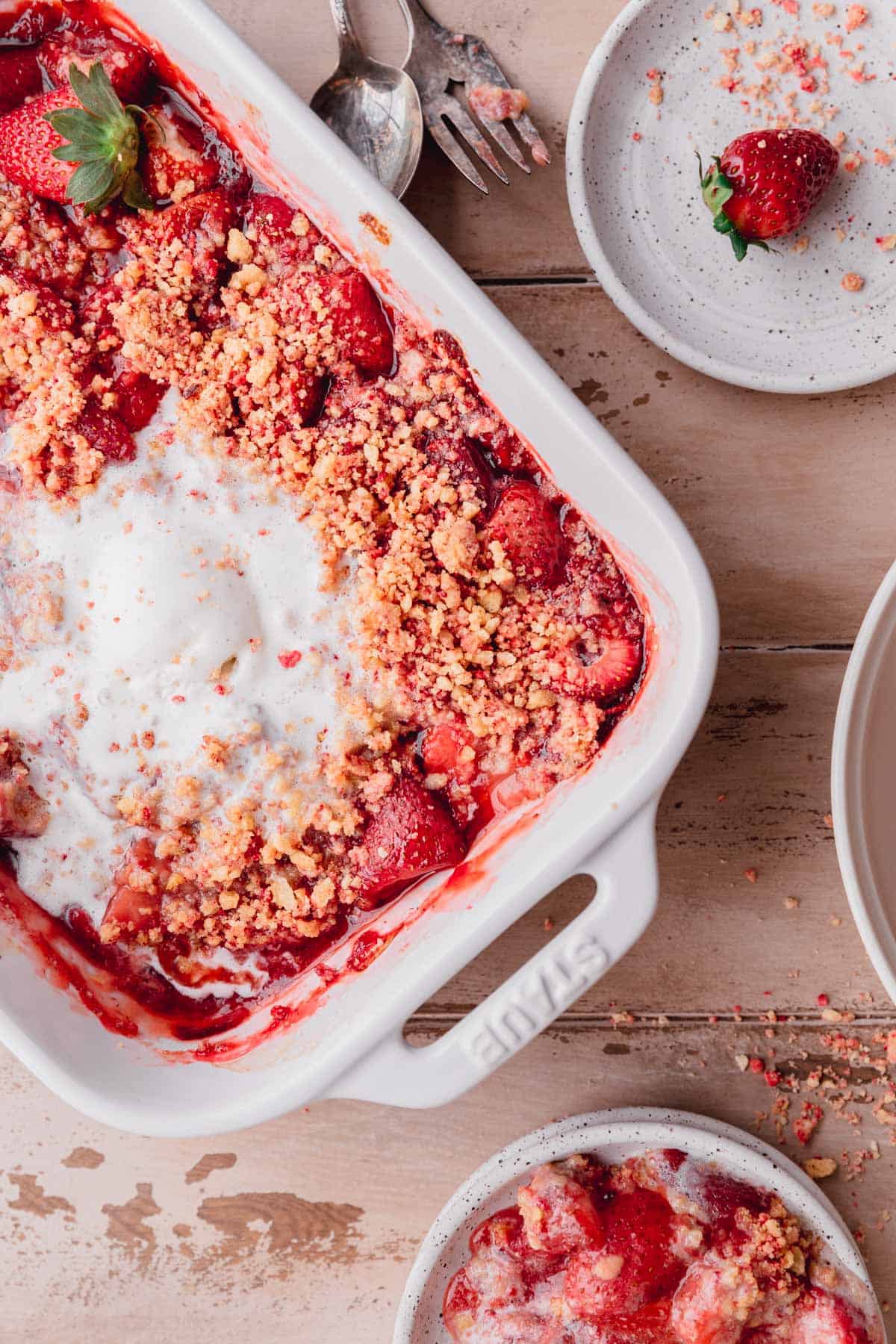 Strawberry Crumble topped with ice cream in a white baking dish.
