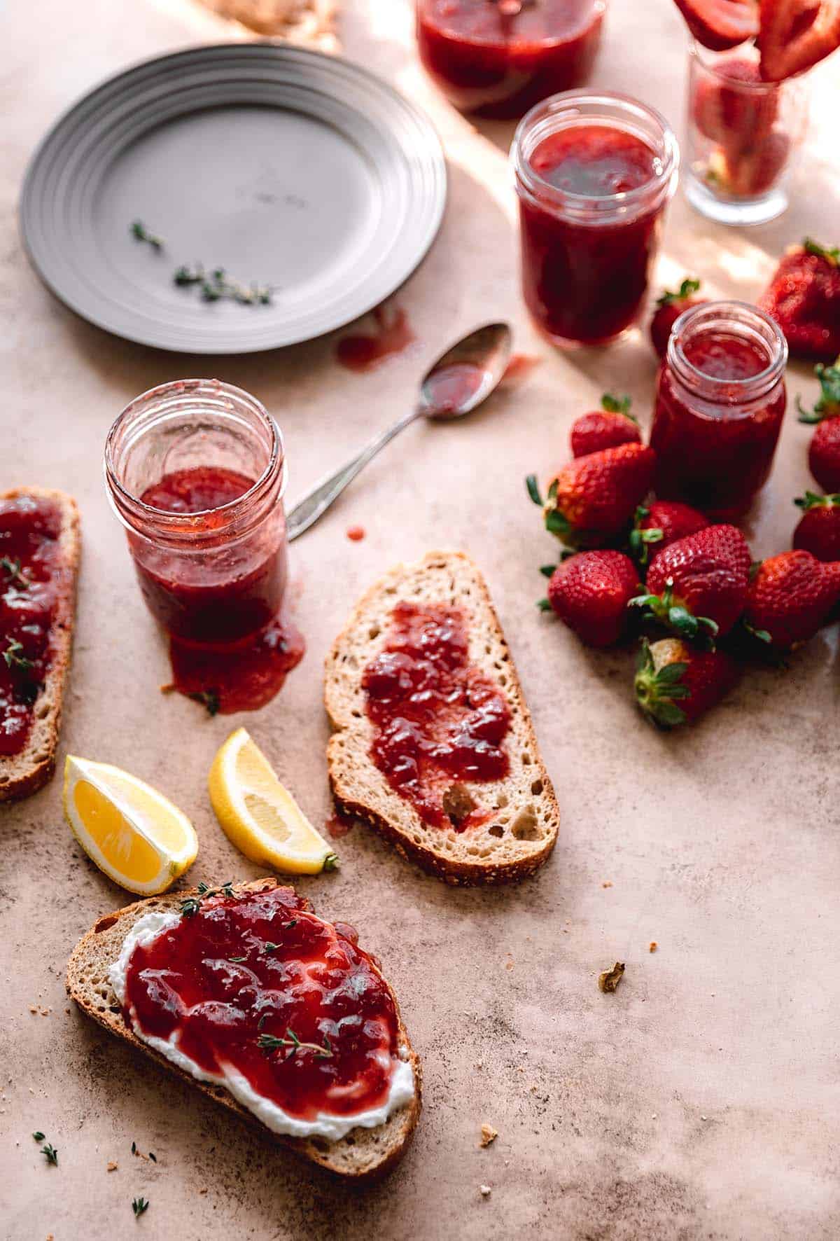 Strawberry jam in jars with slices of sourdough slathered in jam.