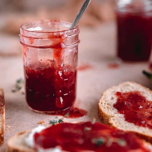 the best strawberry jam in a jar with a drip coming down the side and pieces of toast with jam on them