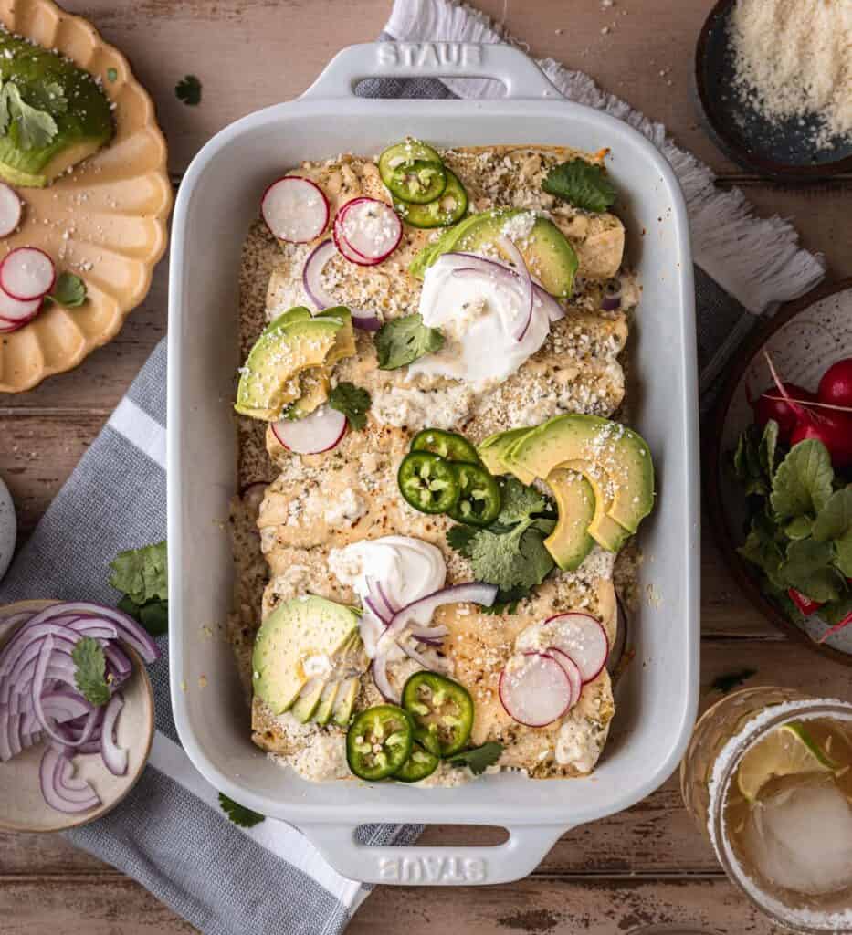 a full pan of creamy green chile chicken enchiladas with toppings