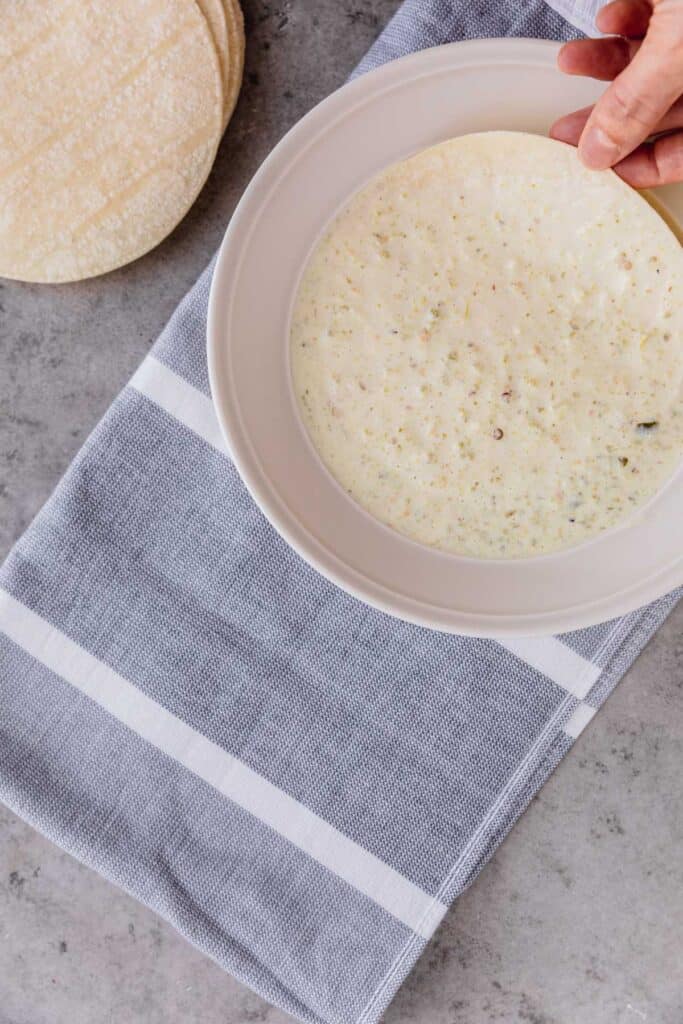 dipping tortilla in enchilada sauce