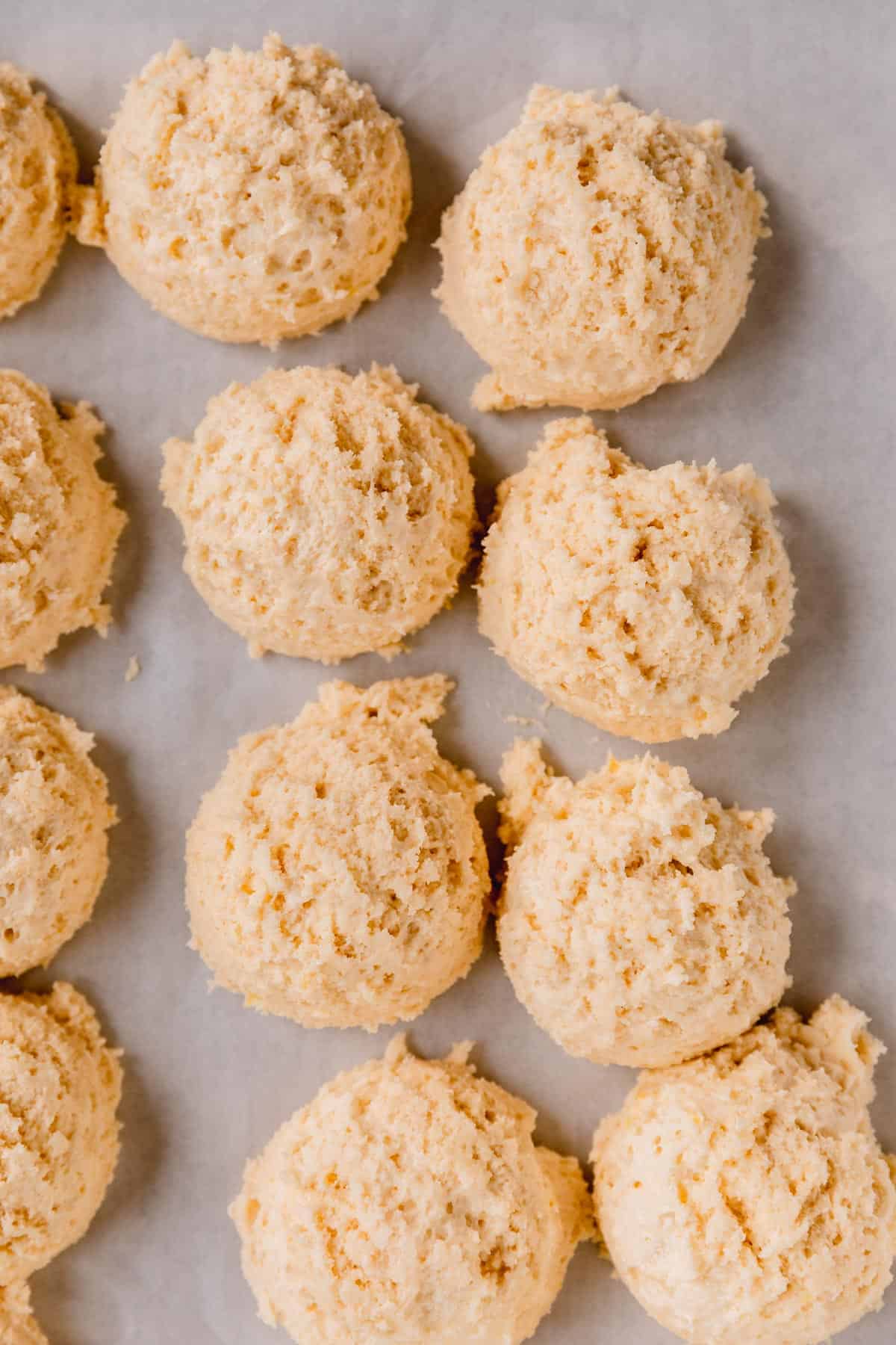 Lemon ricotta cookies scooped onto a parchment lined sheet tray to chill. 