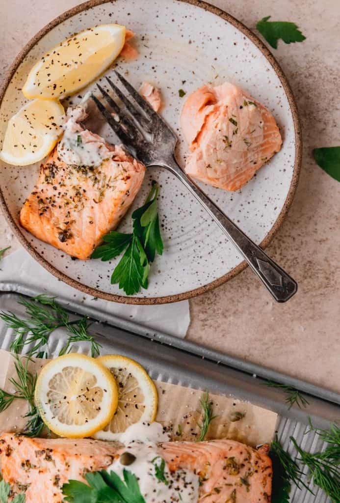 a piece of salmon on a plate cut into with a fork