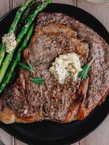 Juicy Air Fryer Ribeye Steak with compound butter and asparagus.