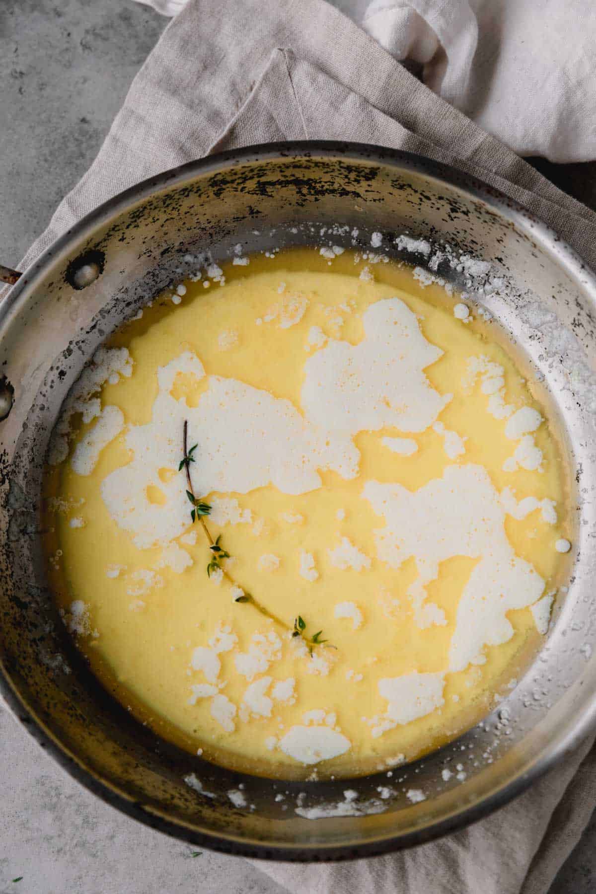Melted butter in a small pan with fresh thyme.
