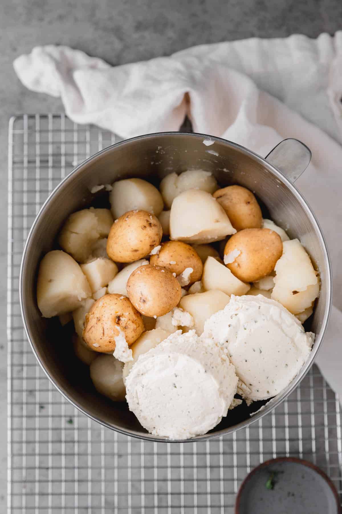 Potatoes, salt, butter, milk and Boursin cheese in the bowl of a stand mixer.