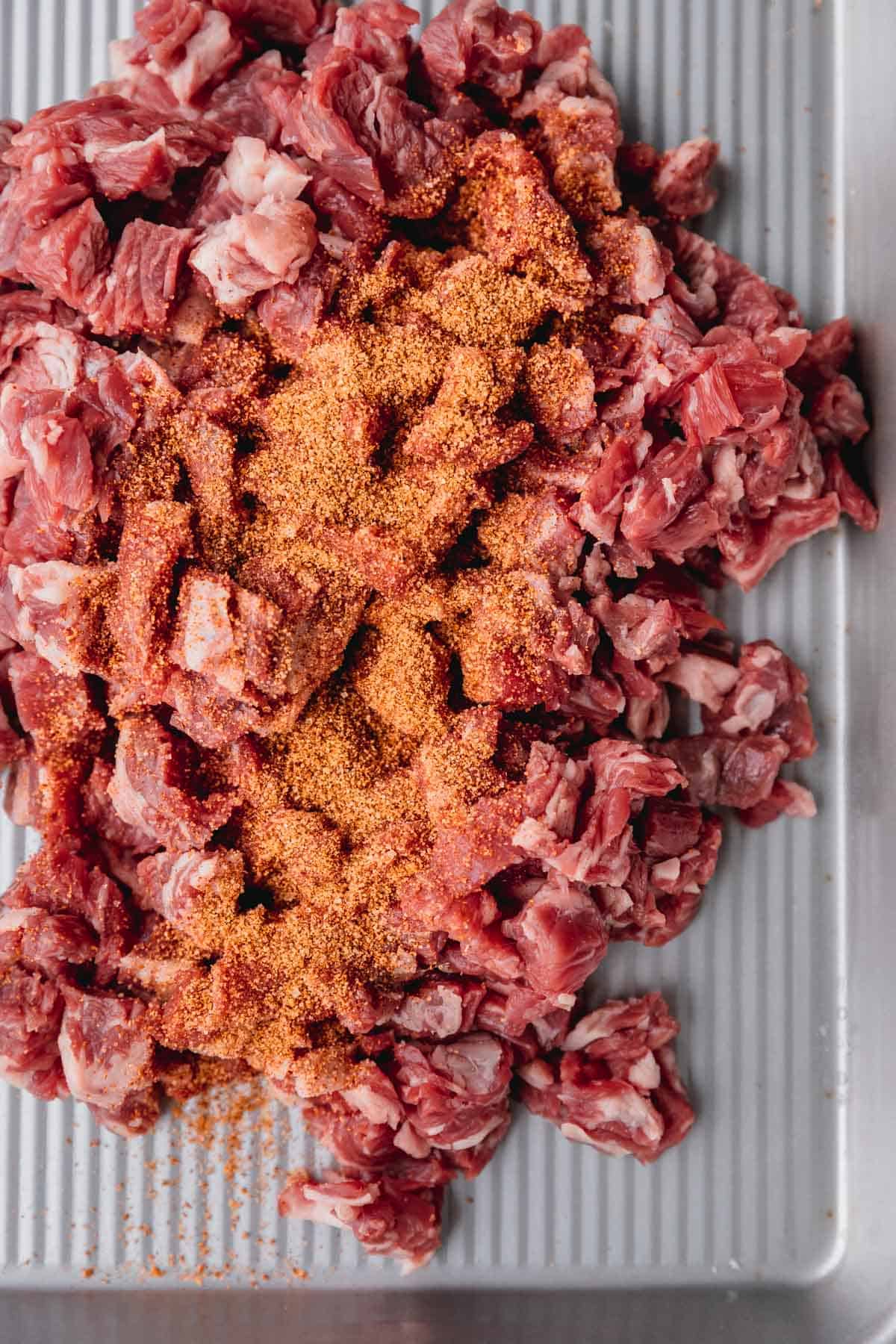 Raw steak cut into cubes with Chef Merito seasoning right before being cooked. 