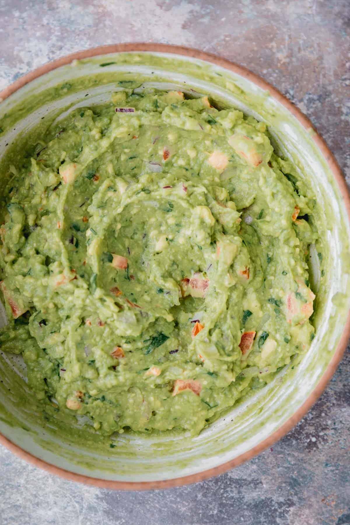Guacamole mixture stirred together in a bowl. 