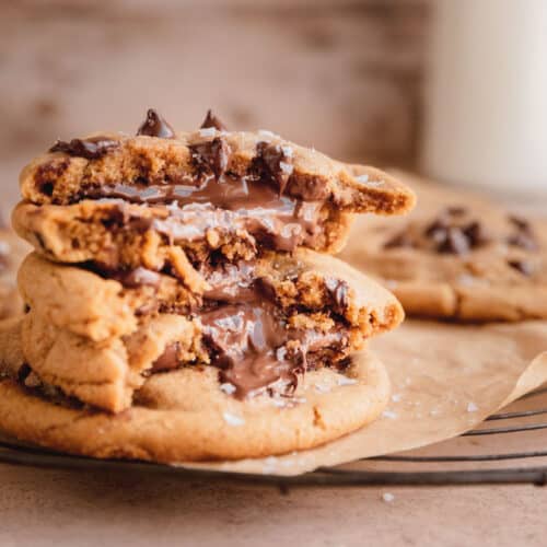 Nutella stuffed chocolate chip cookies broken in half with gooey Nutella coming out
