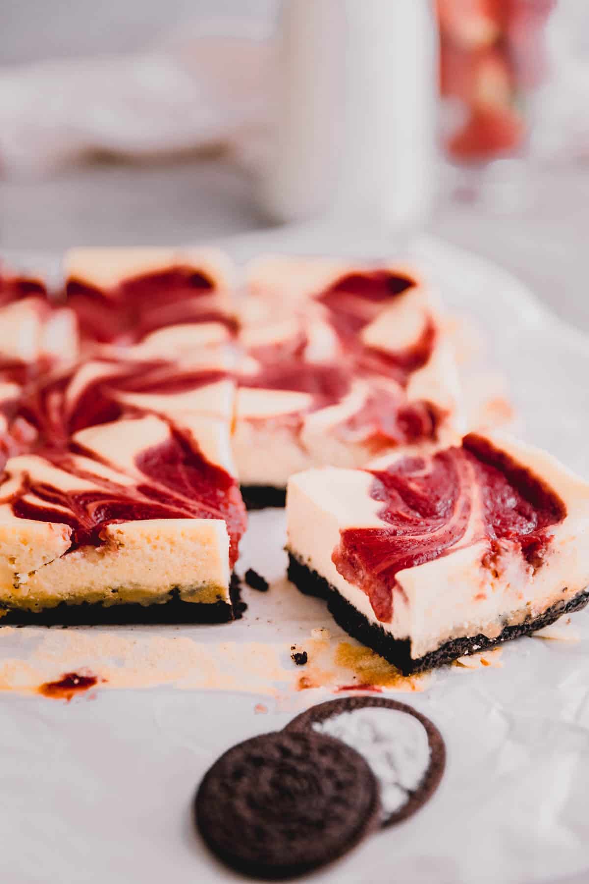 Strawberry cheesecake bars cut on parchment paper.