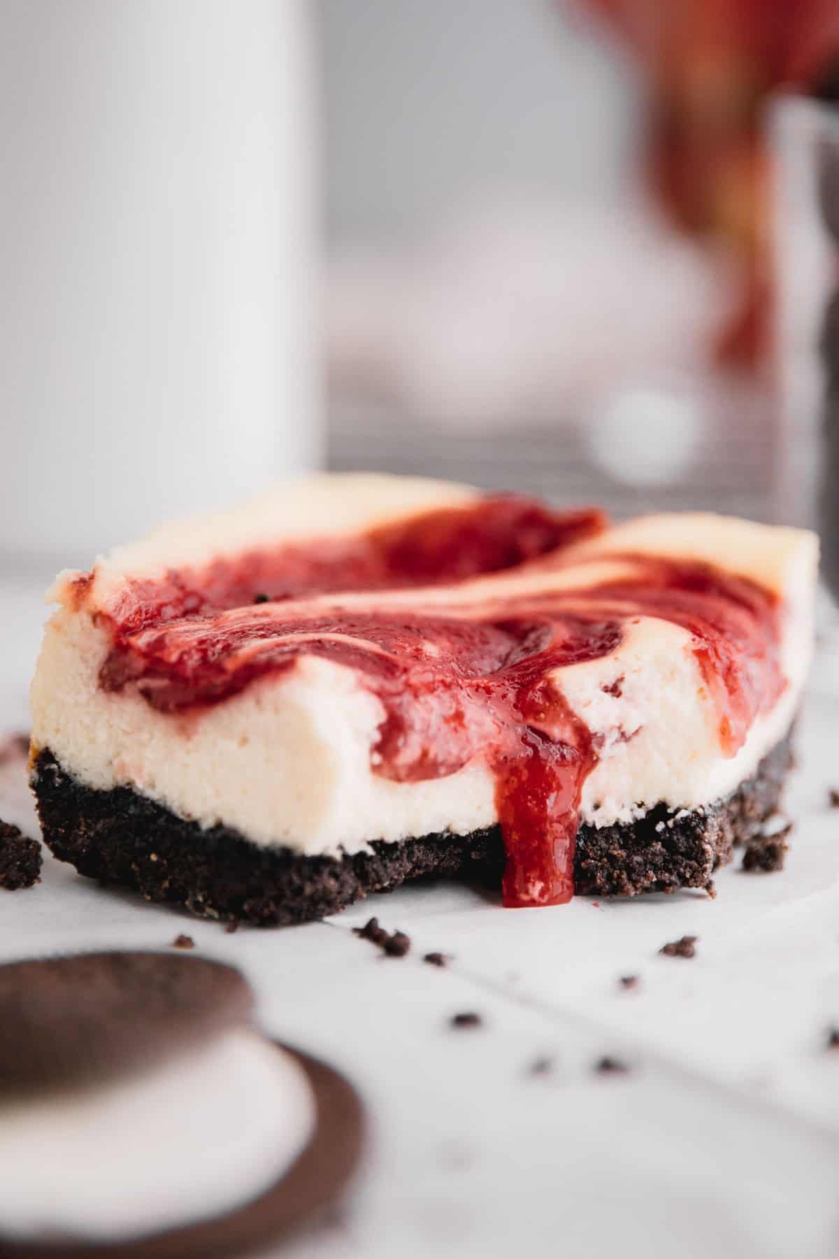 A strawberry cheesecake bar with strawberry sauce dripping down where a bite was taken out.