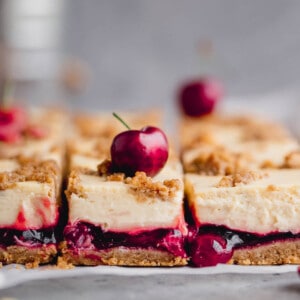 Amaretto Cherry Cheesecake Bars with a cherry filling and fresh cherry on top.
