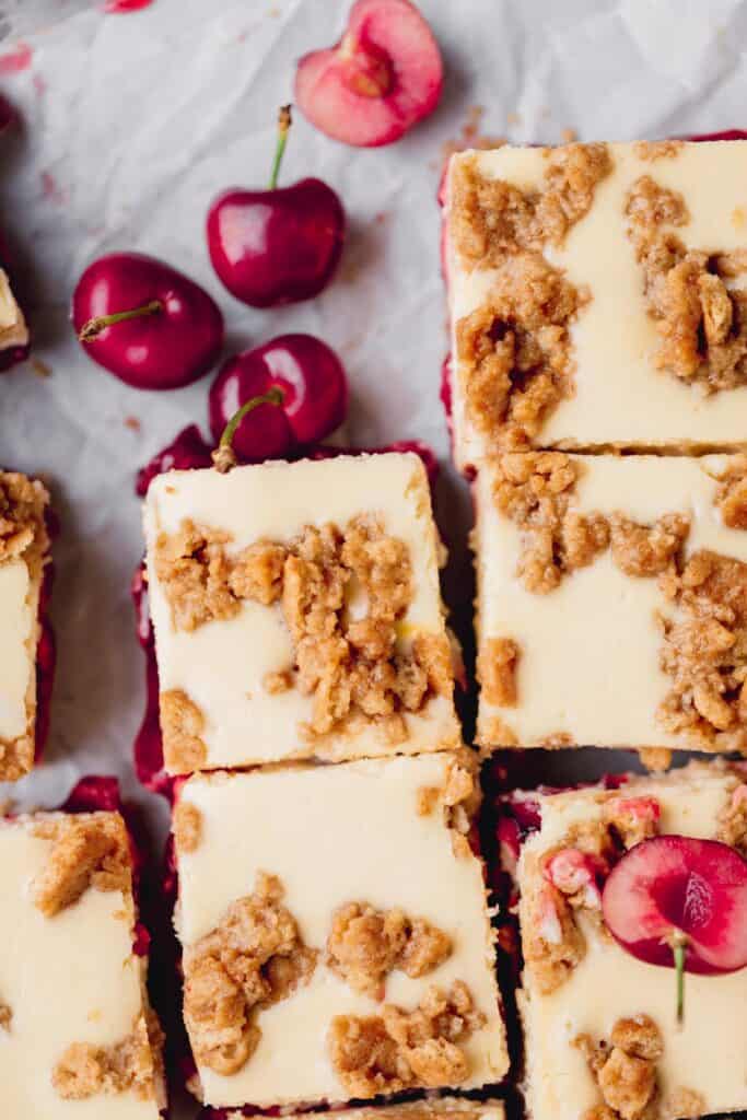 amaretto cherry cheesecake bars cut into squares with fresh cherries to the side 