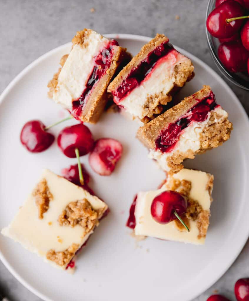 amaretto cherry cheesecake bars cut into squares on a plate with a few on their sides to see the filling 