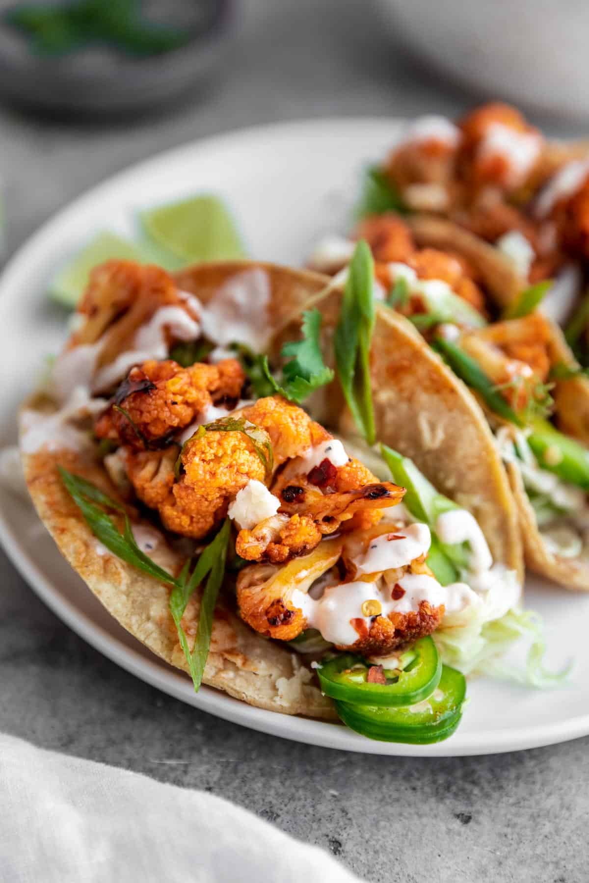 Spicy Buffalo Cauliflower Tacos with green onions, white sauce and jalapenos. 