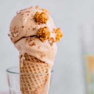 Two scoops of Dulce de Leche Ice Cream topped with caramel popcorn in a sugar cone.
