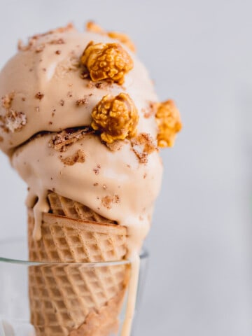 Two scoops of Dulce de Leche Ice Cream topped with caramel popcorn in a sugar cone.