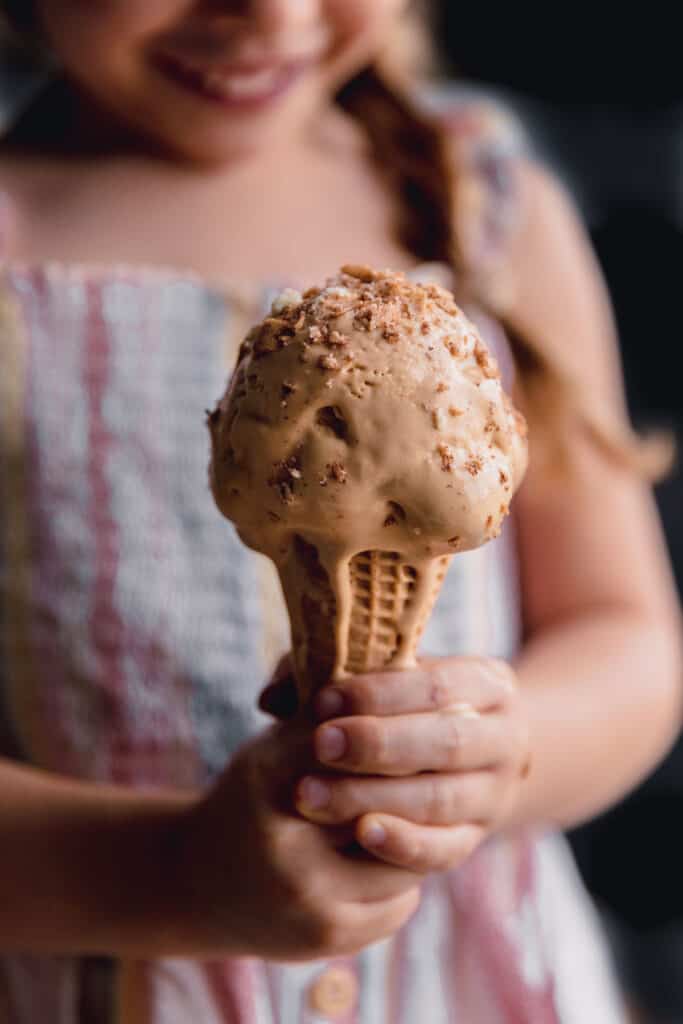 little girl holding an ice cream cone while it tarts to melt