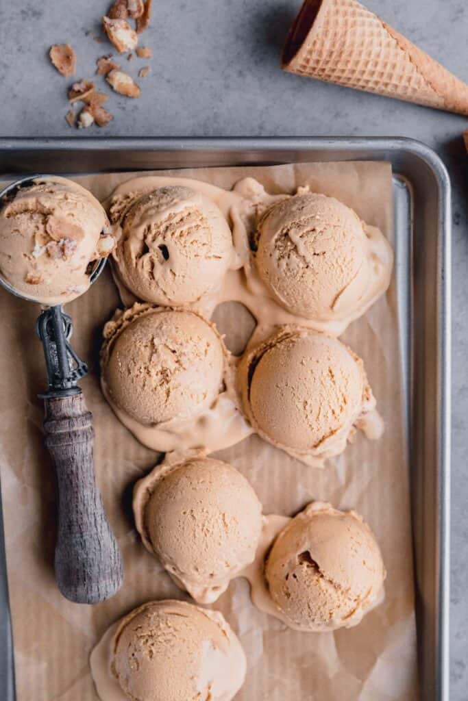 scoops of dulce de leche ice cream on a tray with an ice cream scooper
