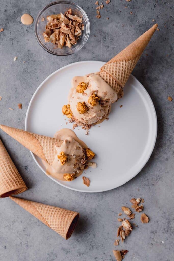 dulce de leche ice cream in cones lying on a plate with caramel popcorn on top