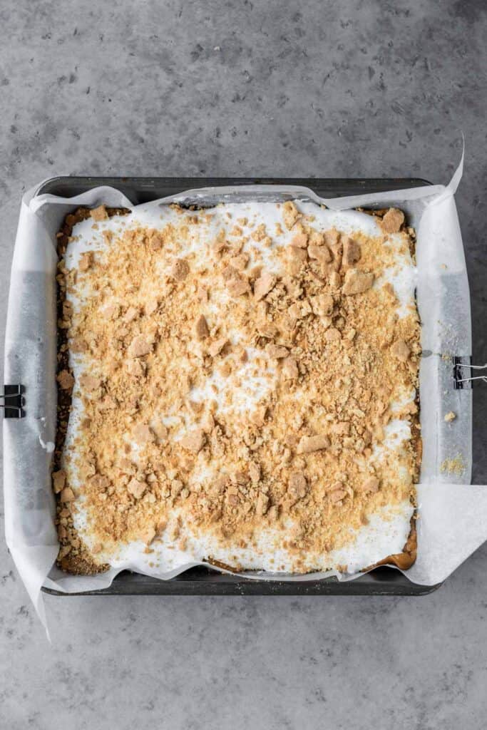 crushed graham cracker on top of the marshmallow fluff layer of the easy s'mores cookie bars