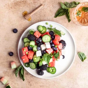 Watermelon Basil Salad with feta, cucumber and berries on a plate.