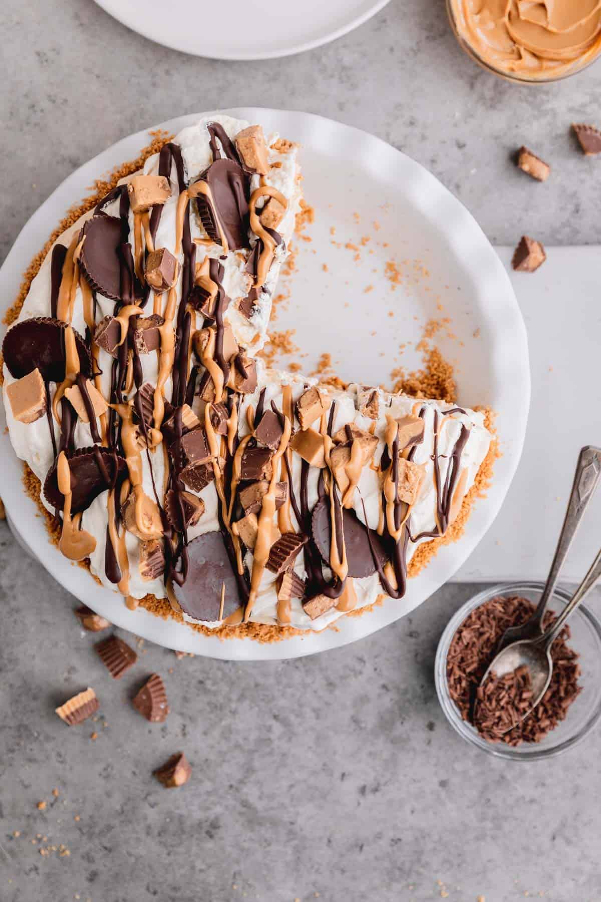 Reese's Peanut Butter Cups Pie in a white pie dish with a couple slices taken out. 