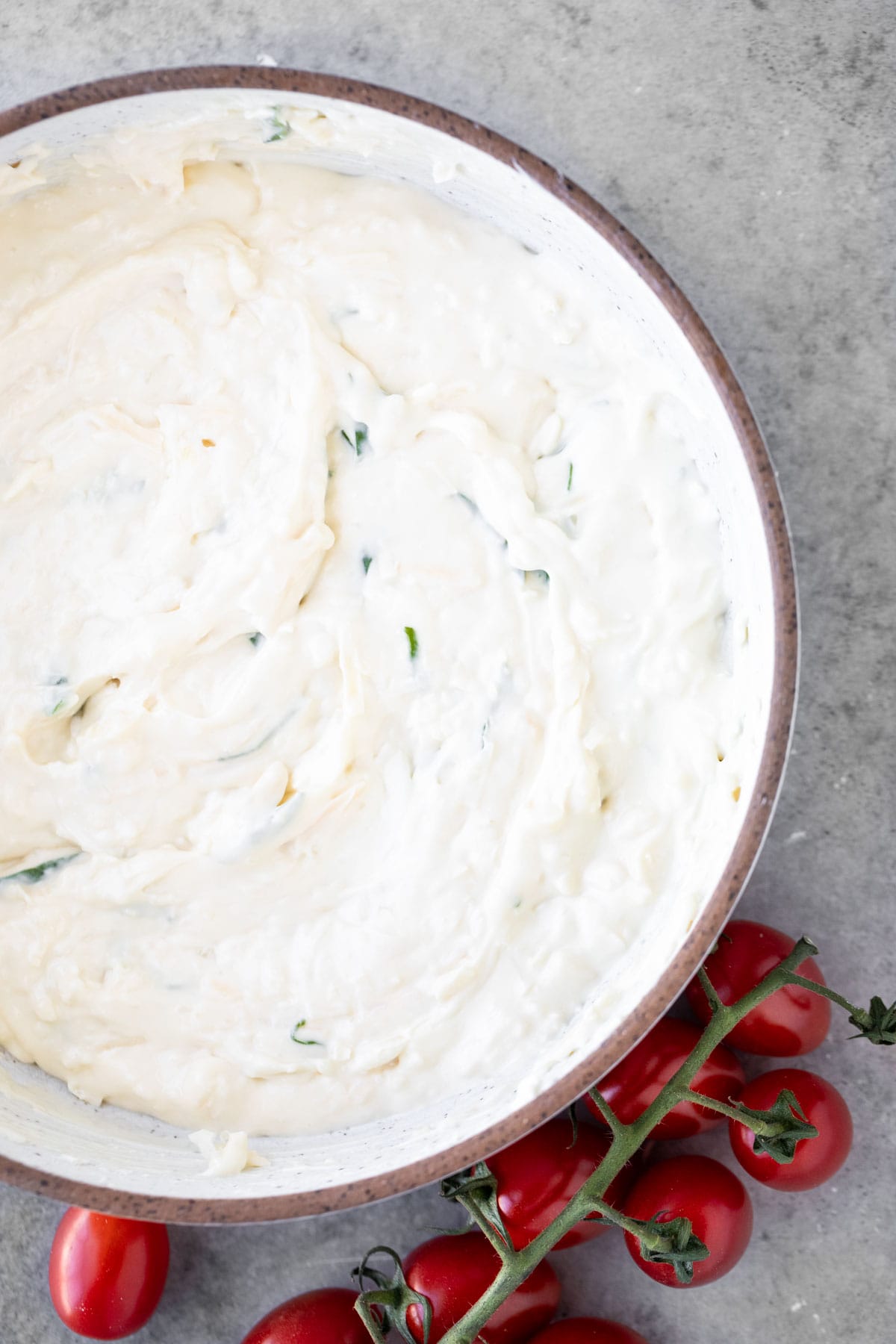 Creamy cheese mixture in a bowl with garlic and basil.