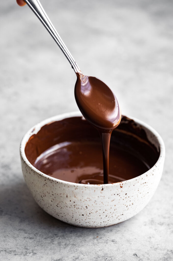 Melted chocolate in a bowl. Melted chocolate dripping off a spoon into the bowl.