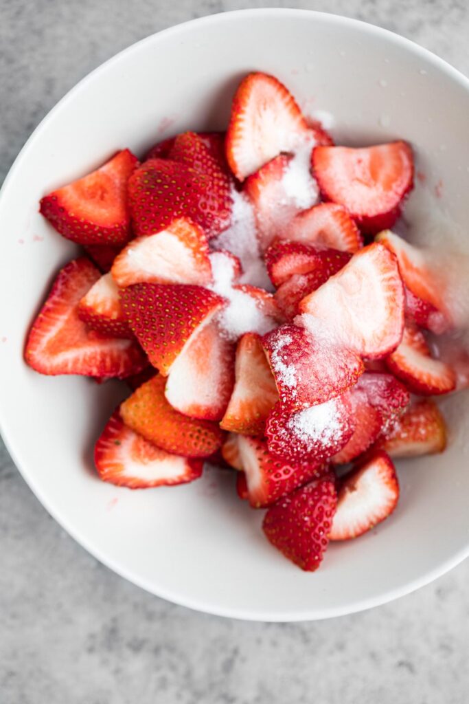 A bowl of sliced strawberries with sugar and lemon juice.