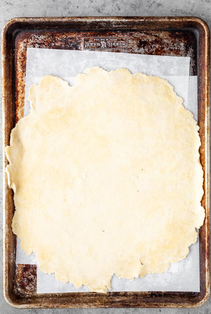 Galette crust rolled out and transferred onto a parchment lined sheet tray.
