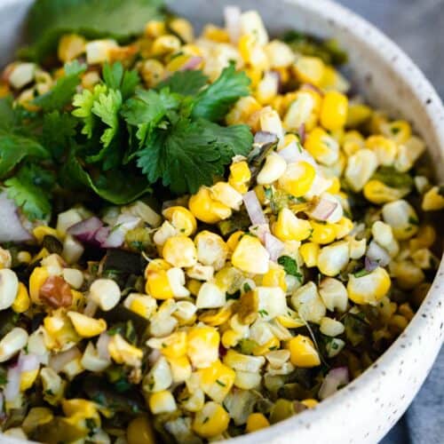 copycat chipotle roasted chili corn salsa in a bowl topped with cilantro leaves
