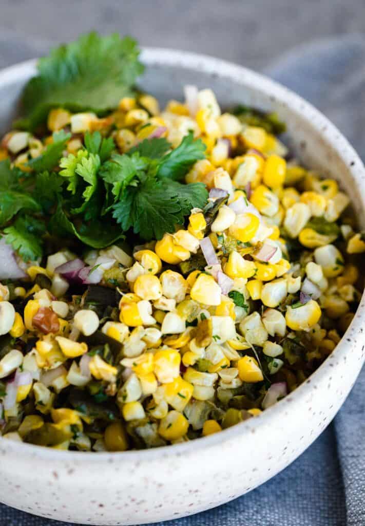 copycat chipotle roasted chili corn salsa in a bowl topped with cilantro leaves 