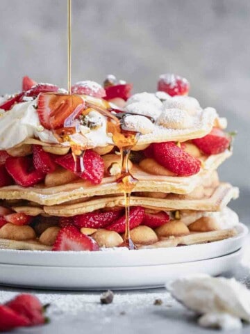 Bubble Waffles stacked with strawberries, cream, pistachios and syrup.