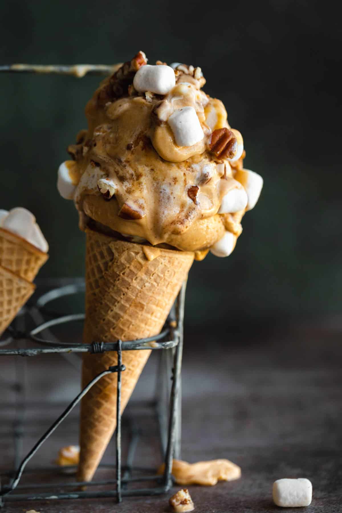 Sweet Potato Ice cream with marshmallows and pecans in a cone sitting in a metal rack. 