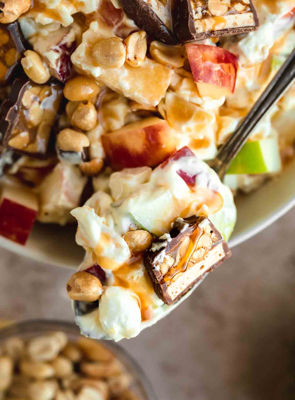 Taffy Apple Salad on a spoon with a chunk of Snickers bar and caramel. 