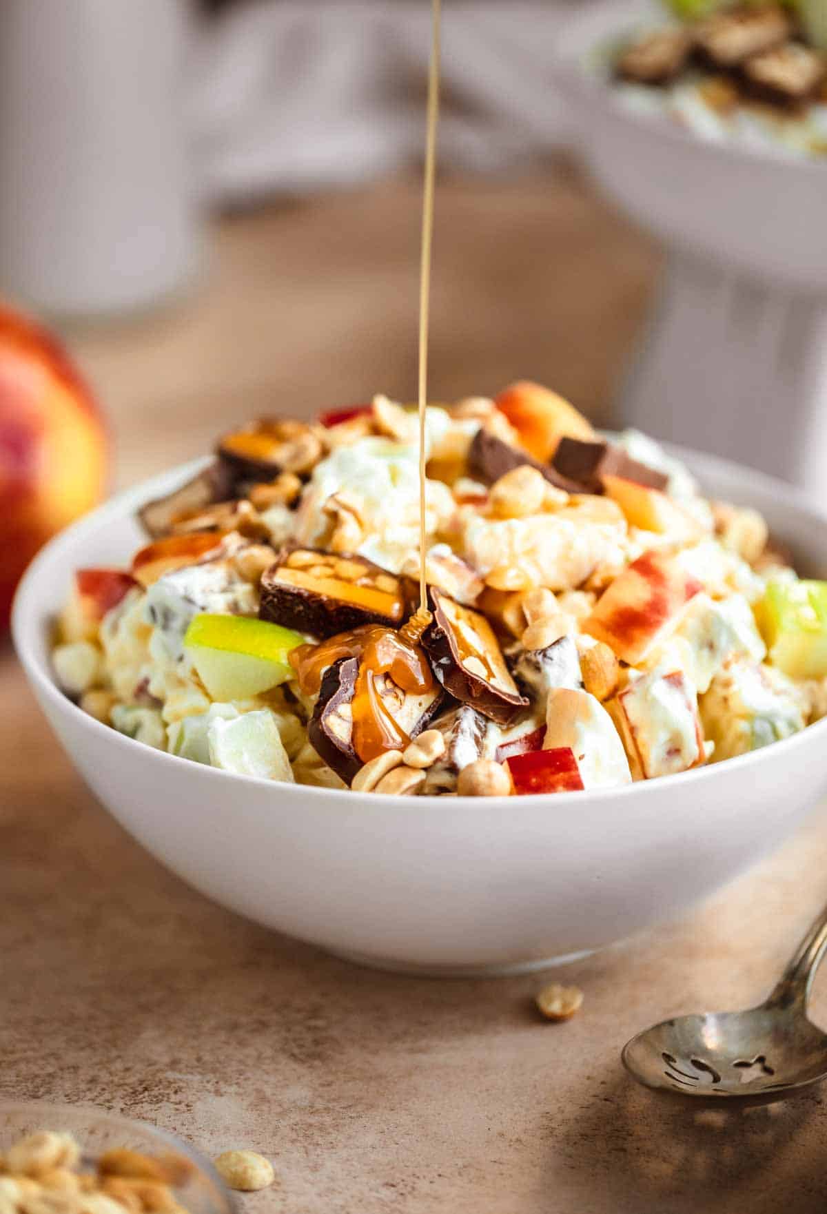 Taffy Apple Salad in a bowl with caramel sauce being drizzled in.