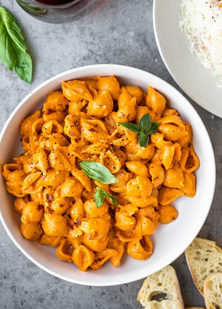 A bowl filled with Gigi Hadid's spicy vodka pasta topped with fresh basil leaves.