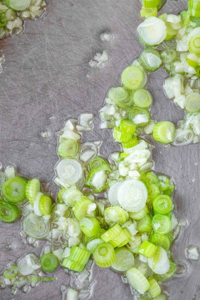 Green onions sautéing in a pan.