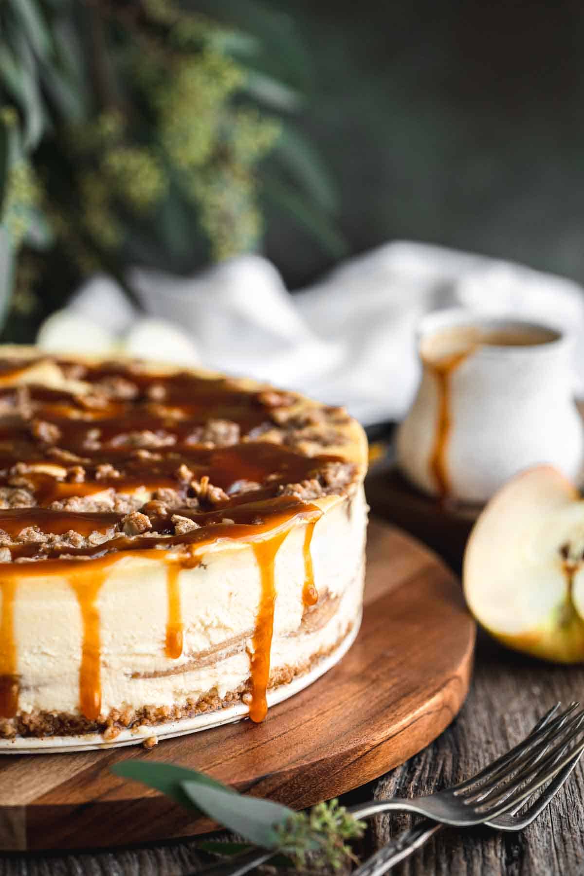 Apple Pie Stuffed Cheesecake with caramel sauce on top and running down the sides. 