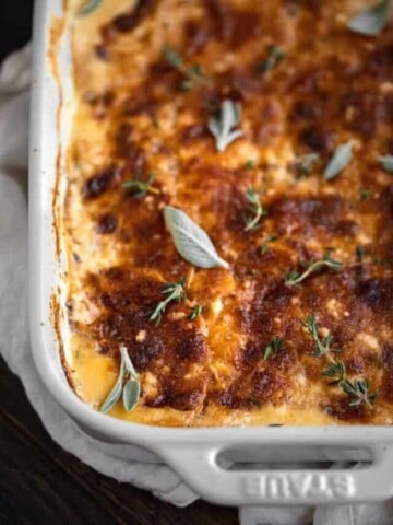 Baked sweet potato au gratin right out of the oven topped with fresh sage and thyme.