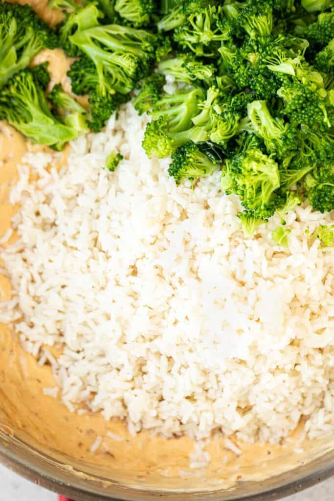 Broccoli and rice being added to the cheese sauce pan.