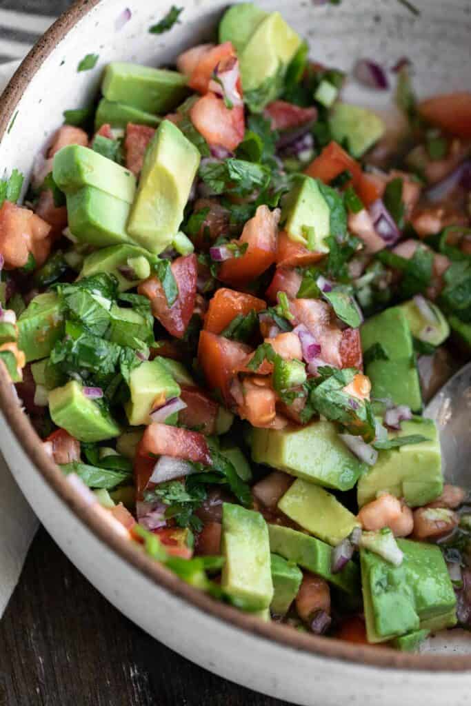 Pico de Gallo mixed together in a medium sized white speckled bowl with a brown rim.