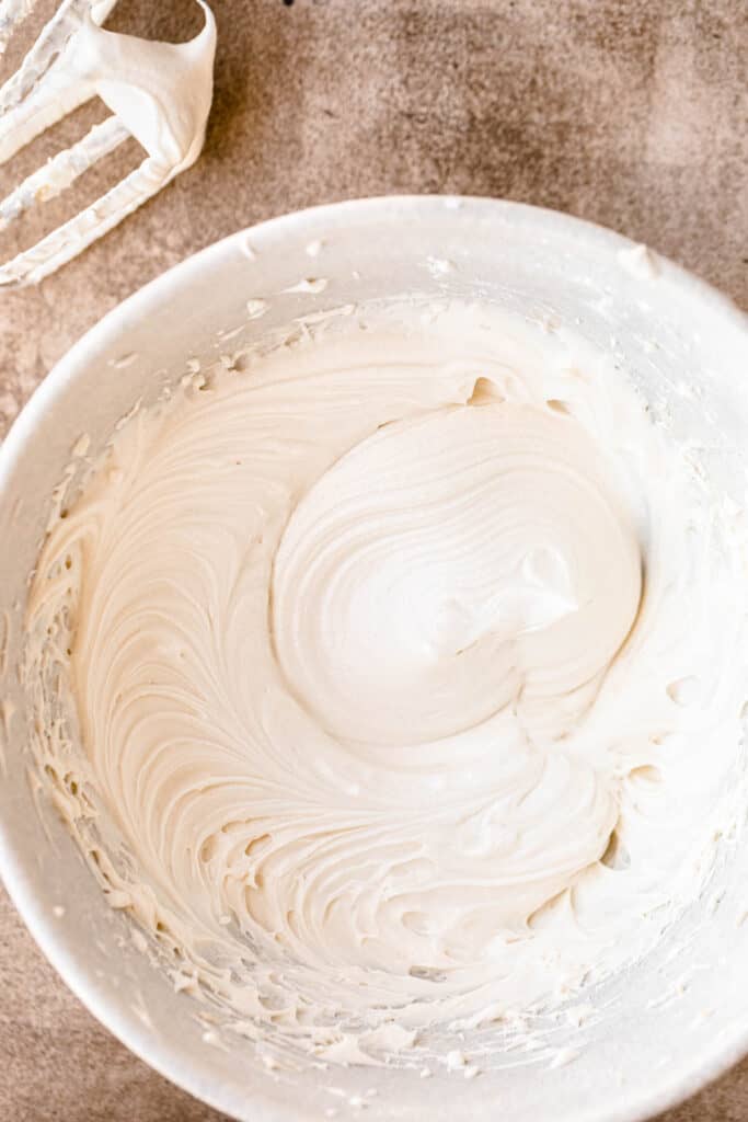 Cream cheese frosting beaten in a white bowl.