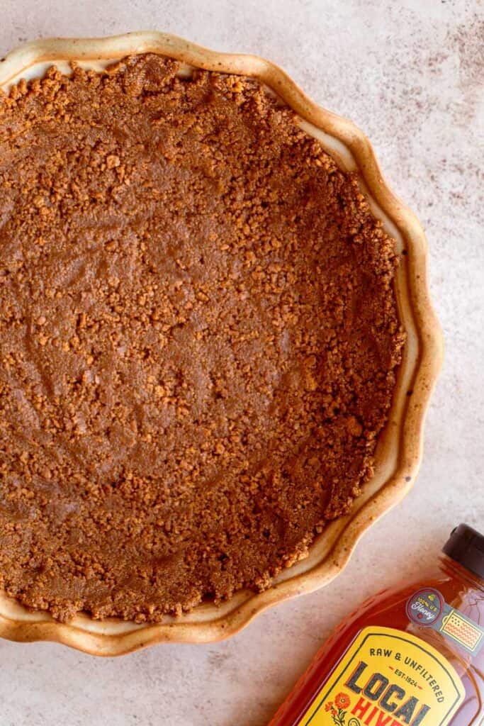 Baked cookie crust with a bottle of honey next to it,