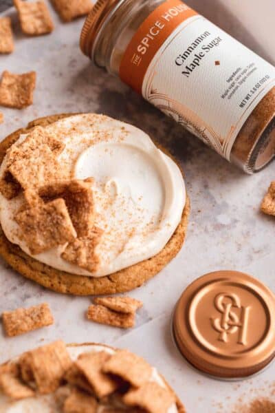 A cookie with frosting and cereal on top with a bottle of cinnamon maple sugar.