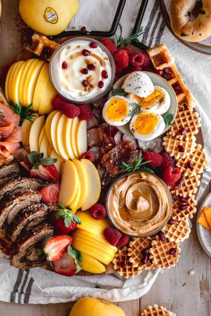Breakfast charcuterie board filled with apples, spreads, fresh fruits, breads, pastries and proteins. 