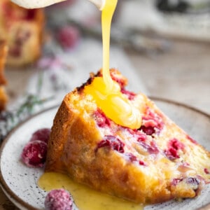 A slice of Cranberry Cake with Butter Sauce being poured onto it.