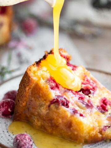 A slice of Cranberry Cake with Butter Sauce being poured onto it.