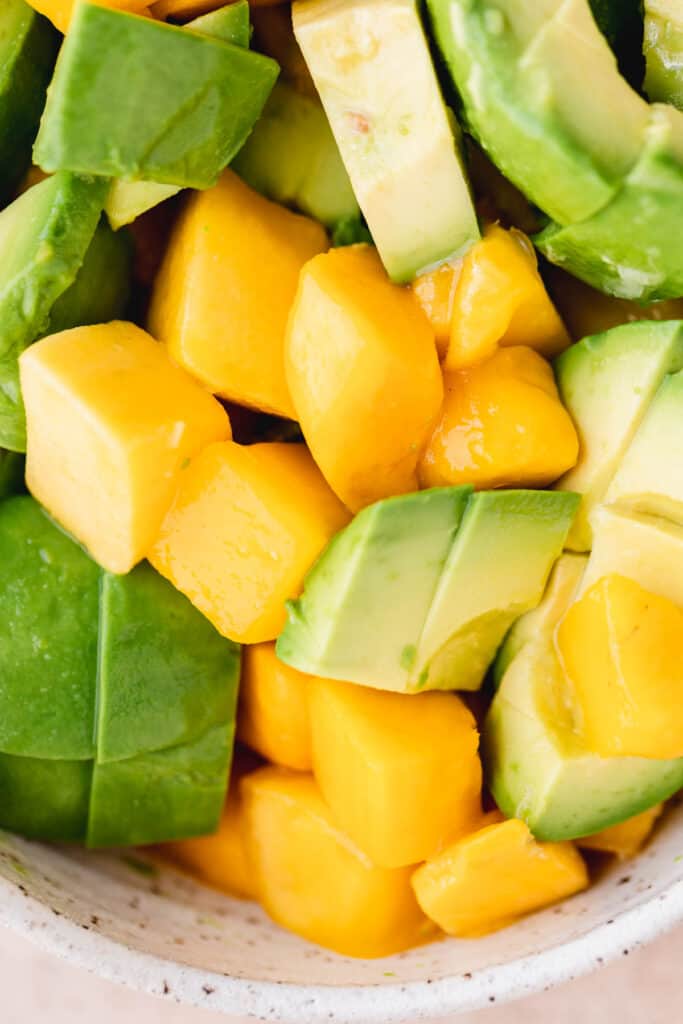 Mango, avocado and lime juice mixed in a bowl.